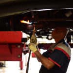 A mechanic welding a car part