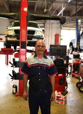 An elevated car behind an auto mechanic